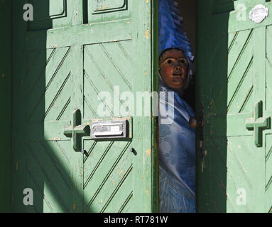 Mittenwald, Germany. 28th Feb, 2019. The leading dancer of the Mittenwald bell stirrers looks through the door before the traditional carnival procession. With the bells they ring in the spring in Upper Bavaria. Credit: Angelika Warmuth/dpa/Alamy Live News Stock Photo