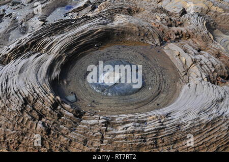 Detail of tiny round rock pool in middle of eroded volcanic rock showing details of circular layers of stone material. Stock Photo