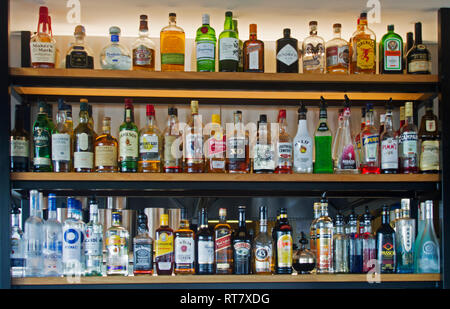 Shelves crammed with colourful array of bottles of alcoholic drinks in a bar / pub Stock Photo