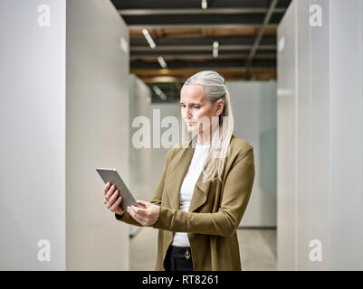 Businesswoman using tablet on office floor Stock Photo
