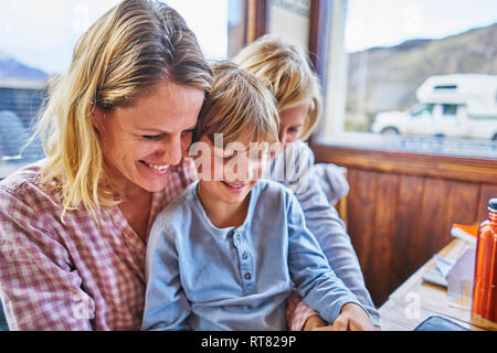 Happy mother with two sons sitting at table in a cafe Stock Photo