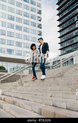 Two colleagues walking and talking on stairs outside office building in the city Stock Photo