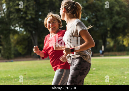Granddaughter and grandmother having fun, jogging together in the park Stock Photo