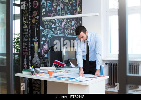 Businessman at desk in office looking at printouts Stock Photo