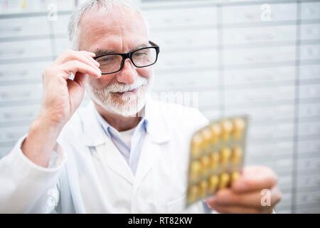 Smiling pharmacist holding tablet package in pharmacy Stock Photo