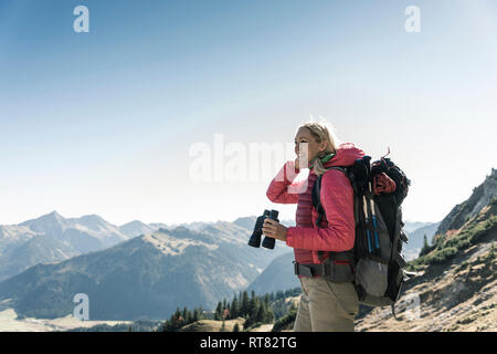 Austria, Tyrol, smiling woman with binoculars on a hiking trip Stock Photo