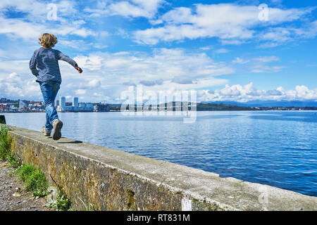 Chile, Puerto Montt, boy running on quay wall at the harbor Stock Photo