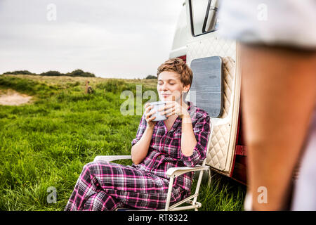 Woman in pyjama enjoying coffee at a van in rural landscape Stock Photo