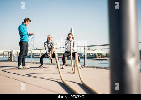 Friends training at the riverside, pulling rope Stock Photo