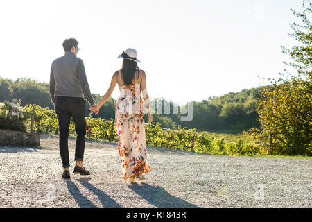 Italy, Tuscany, Siena, young couple walking hand in hand in a vineyard Stock Photo
