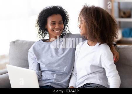 African mother and daughter sitting on couch using computer Stock Photo