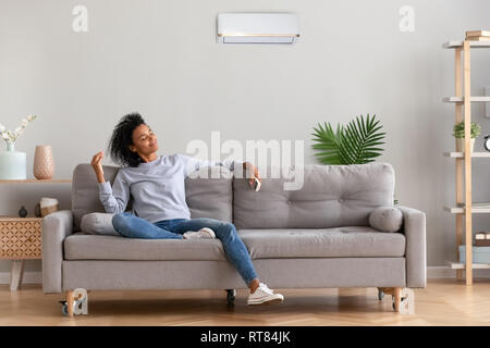 African young relaxed woman sitting on couch breathing fresh air Stock Photo