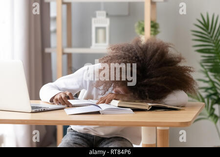 Schoolgirl sleeping sitting at desk in classroom during study Stock Photo