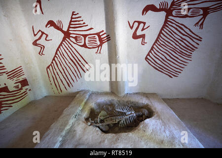 An exposed skeleton which were found in pits under the floors of some houses. On the wall are frescoes of what look like vultures, Scholars belive tha Stock Photo