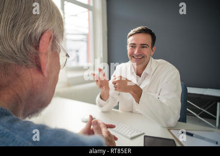 Smiling doctor talking to patient in medical practice Stock Photo
