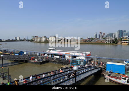 Boat passengers walk towards land across a bridge from the pier on the River Thames at Greenwich in London, United Kingdom. Stock Photo