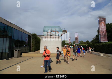 People walk past a replica of Lord Nelson's HMS Victory ship in a bottle, outside the Sammy Ofer Wing museum in Greenwich, London, United Kingdom. Stock Photo