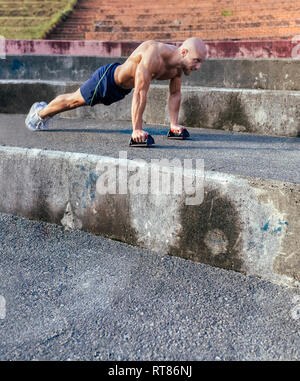 Barechested muscular man doing push-ups outdoors Stock Photo