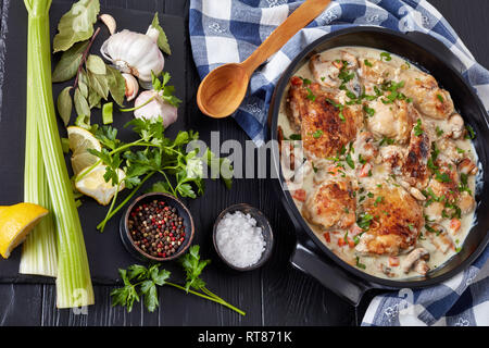 chicken fricassee in a black dutch oven - chicken meat browned and braised in white wine creamy sauce with mushrooms and vegetables, classic french cu Stock Photo