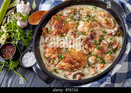 chicken fricassee in a black dutch oven - chicken meat browned and stewed in white wine creamy sauce with mushrooms and vegetables, classic french rec Stock Photo