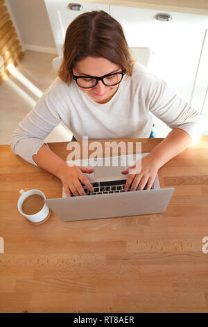Top view of womans hands typing on laptop keypad wearing glasses and coffee on the table. Mock up minimal flat lay hero header Stock Photo