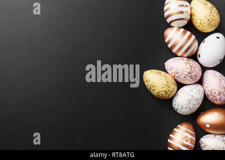 Easter concept. Golden eggs with stripes and dots on black background. Flat Lay. Stock Photo