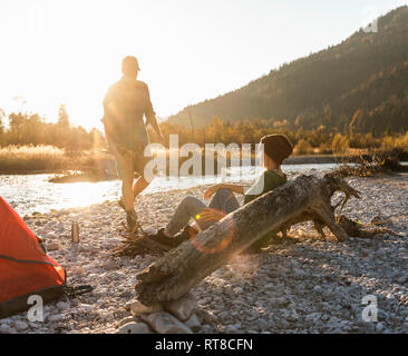 Mature couple camping at riverside, collecting wood for a camp fire Stock Photo