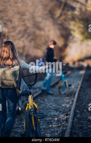 Boy and girl walking on the train track with bicycles