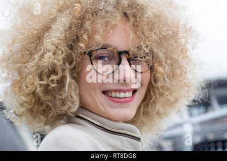 Portrait of smiling blond woman with ringlets wearing fashionable glasses