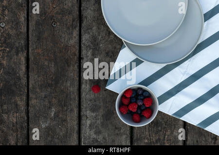 Flat lay, berries in minimalist bowl with wooden planks Stock Photo