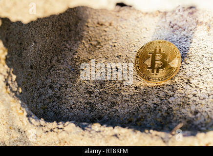 Bitcoin hidden inside a block of concrete between lights and shadows Stock Photo