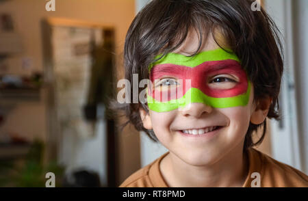 Portrait of smiling boy with face painting - Painted child face on blurry background Stock Photo