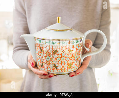 A woman holds a teapot in her hands for brewing tea. The concept of tea drinking. Copy space. Selective frame. Stock Photo
