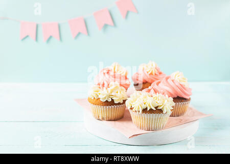 Fresh cupcakes with whipped cream and cream are served on a plate on a festive blue background with flags. Copy space. Stock Photo