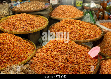Several bags of dried shrimp for sale at Asian food market, pile high in bamboo shallow baskets Stock Photo