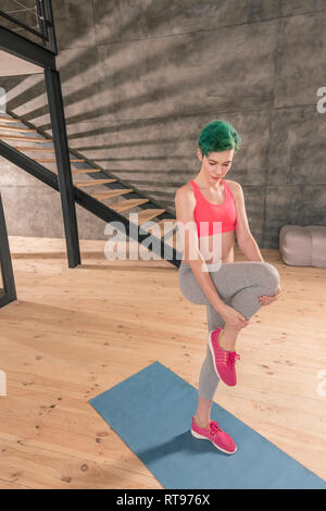 Green-haired woman wearing bright pink top working out at home Stock Photo