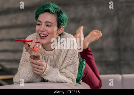 Woman in a good mood holding smartphone and speaking with friend Stock Photo