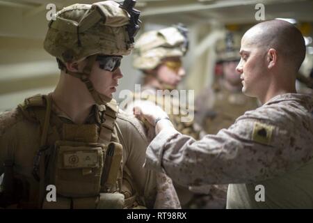 MEDITERRANEAN SEA, Jan. 30, 2019 - U.S. Marine Corps Sgt. Bobby Pittman, a squad leader with the 22nd Marine Expeditionary Unit, inspects his Marines’ equipment while rehearsing pre-combat checks and inspections aboard the San Antonio-class amphibious transport dock ship USS Arlington (LPD 24), Jan. 30, 2019. The USS Arlington is making a scheduled deployment as part of the 22nd MEU and the Kearsarge Amphibious Ready Group, in support of maritime security operations, crisis response and theatre security cooperation, while also providing a forward Naval and Marine presence. Stock Photo