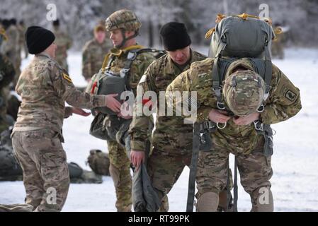 U.S. Army Col. James Bartholomees, first from right, commander of 173rd Airborne Brigade (173rd AB), and Lt. Col. James Peay, third from right, commander of 4th Battalion, 319th Field Artillery Regiment, 173rd AB, have their equipment checked prior to a jump from CH-47 Chinook helicopters with multinational partners from Germany, Spain and the United Kingdom at the 7th Army Training Command's Grafenwoehr Training Area, Germany, Jan. 30, 2019. Stock Photo