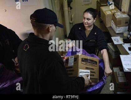 MEDITERRANEAN SEA (Jan. 28, 2019) Logistics Specialist 2nd Class Dylan Deloach, of Joshua, Texas, left, and Hull Maintenance Technician 3rd Class Megan Griffith, of Wake Forrest, N.C. sort mail aboard the San Antonio-class amphibious transport dock ship USS Arlington (LPD 24), Jan. 28, 2019. Arlington is on a scheduled deployment as part of the Kearsarge Amphibious Ready Group in support of maritime security operations, crisis response and theater security cooperation, while also providing a forward naval presence. Stock Photo