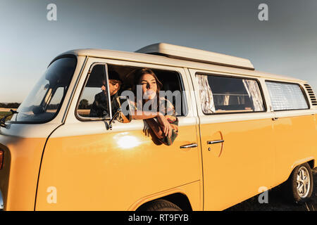 Happy couple sitting in their camper, watching the sunset Stock Photo