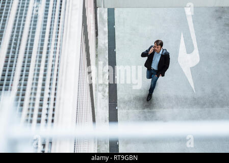 Businessman walking in parking garage, using mobile phone Stock Photo