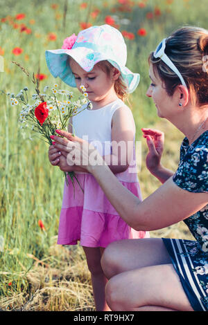 Mother and her little daughter in the field of wild flowers. Little girl picking the spring flowers for her mom for Mother's Day in the meadow. Nature Stock Photo