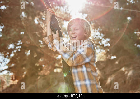 Happy boy swinging on a rope in backlight Stock Photo