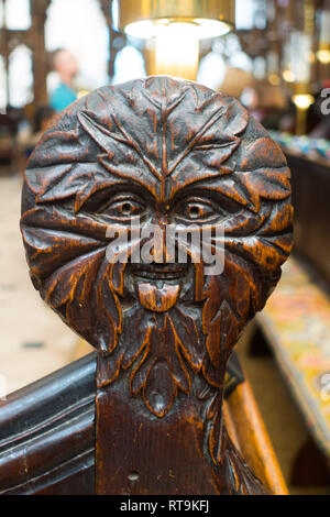 The Green Man with his tongue out towards the altar on the end of the choir stalls in Winchester Cathedral Stock Photo