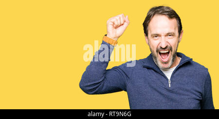 Middle age handsome man wearing a sweater Dancing happy and cheerful, smiling moving casual and confident listening to music Stock Photo