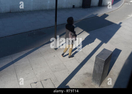 A lady walks into the shadow of a traffic signpost at Elephant & Castle in Southwark, on 25th February 2019, in London, England. Stock Photo