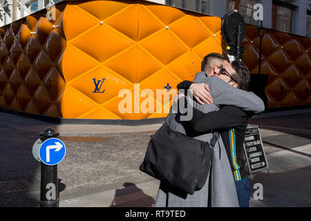 Friends greet each other opposite the temporary renovation hoarding of ...