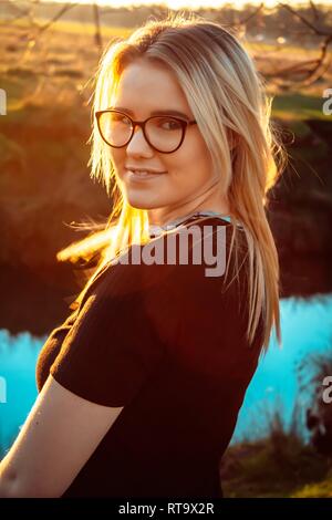 Beautiful woman turns to look at the camera after viewing the sunset in a country park. Stock Photo