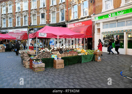 Vegetable stall & row traditional terraced housing above shops on Electric Avenue street market in Brixton South London SW9 England UK KATHY DEWITT Stock Photo